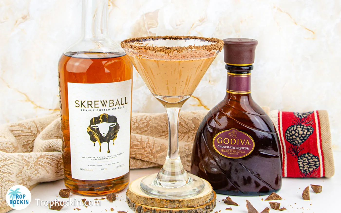 Peanut Butter Whiskey Drink in a martini glass with a bottle of Skrewball Whiskey and a Bottle of Godiva Chocolate Liqueur in the background.