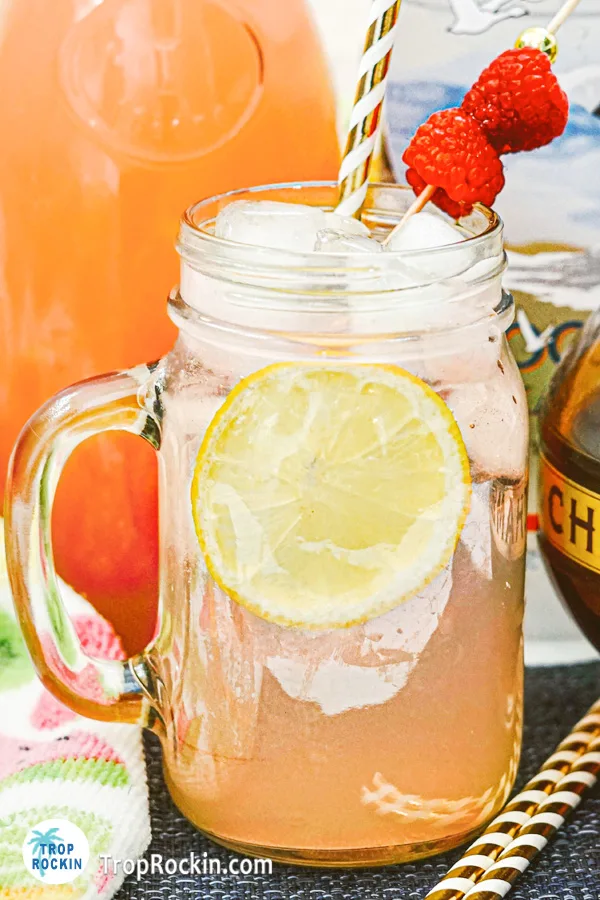 Raspberry Vodka Lemonade up close in a mason jar with skewer of fresh raspberries for garnish.