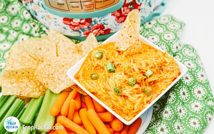 Instant Pot Buffalo Chicken Dip in a bowl with a platter of tortilla chips, celery sticks and carrot sticks with an Instant Pot in the background.
