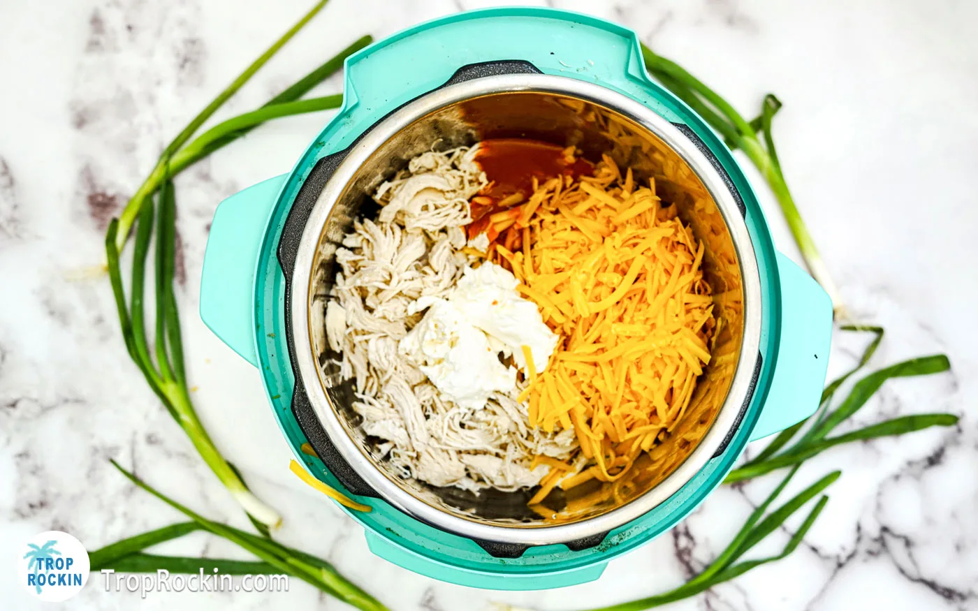 Cream Cheese, Buffalo Sauce and Shredded Cheese added on top of the shredded chicken in the instant pot.