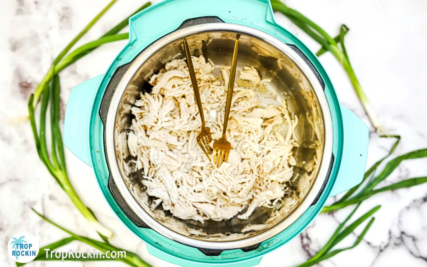 Shredded chicken with two forks inside the instant pot.