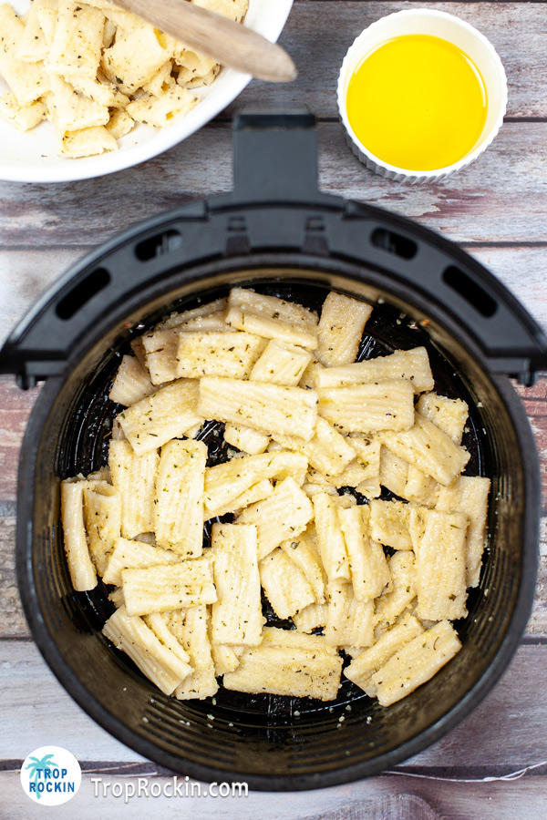 Al dente pasta with cheese and seasoning in the air fryer basket.