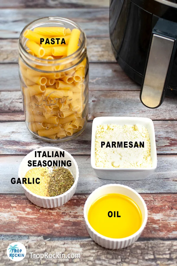 Glass jar of pasta, small bowl of oil, small bowl with garlic and italian seasoning and bowl of grated parmesan cheese.