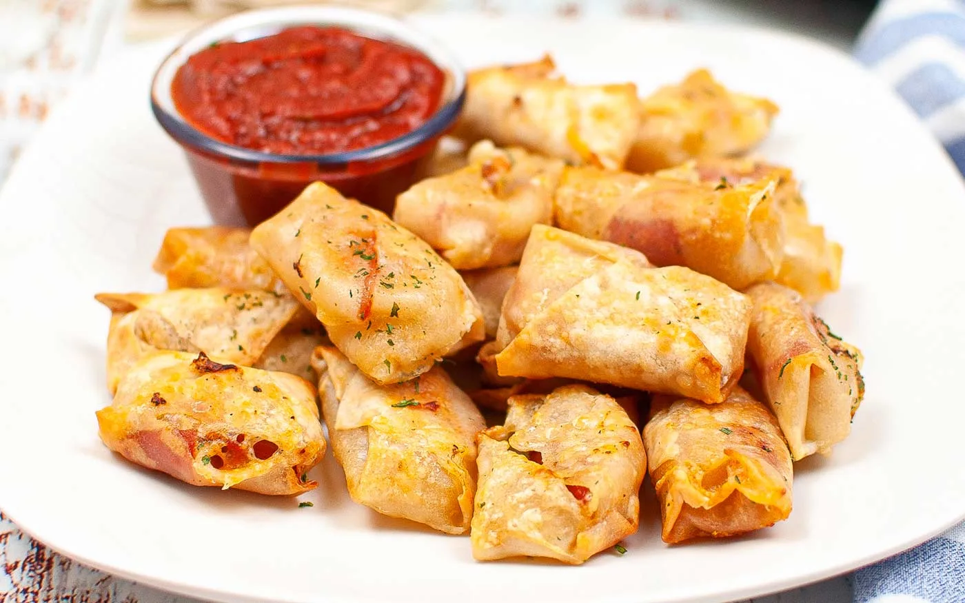 Air Fryer Pizza Egg Rolls on a plate with a small bowl of pizza sauce.