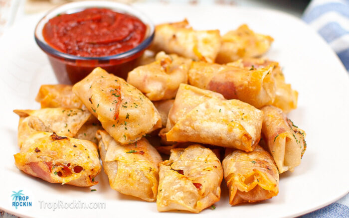 Air Fryer Pizza Egg Rolls on a plate with a small bowl of pizza sauce.