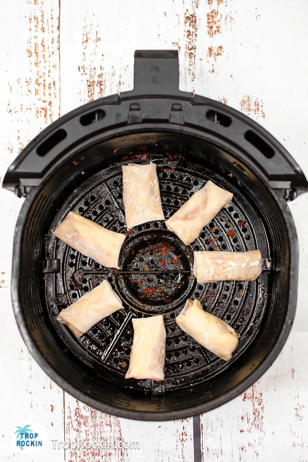 Pizza egg rolls inside the air fryer basket in a single layer.