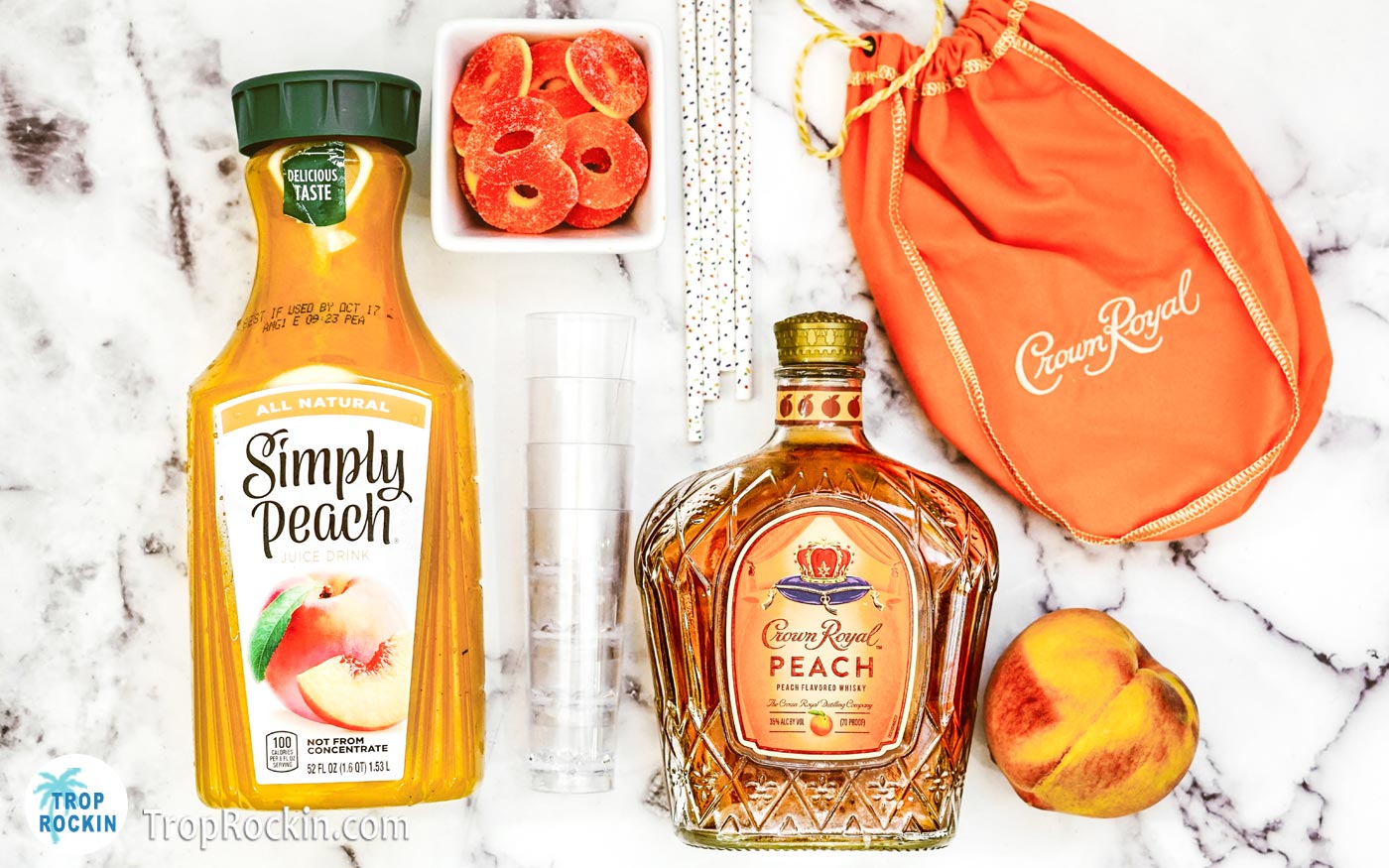 Crown Royal Peach Shots ingredients flatlay with shot glasses and paper straws.