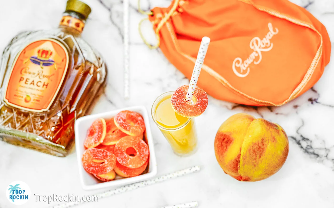 Single shot with crown royal peach bottle in background and a bowl of peach rings.
