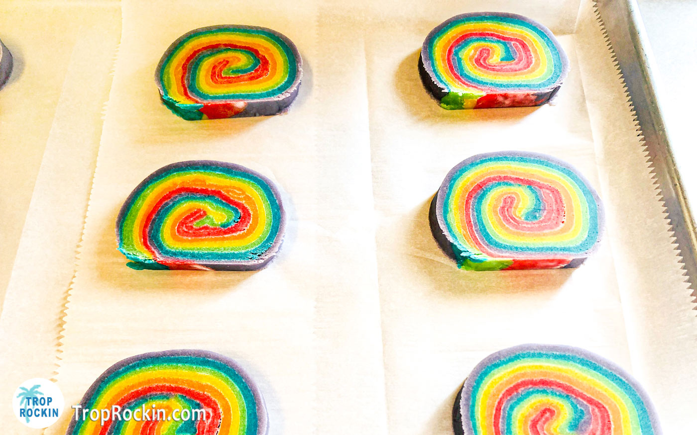 Sliced rainbow cookies on baking sheet lined with parchment paper.