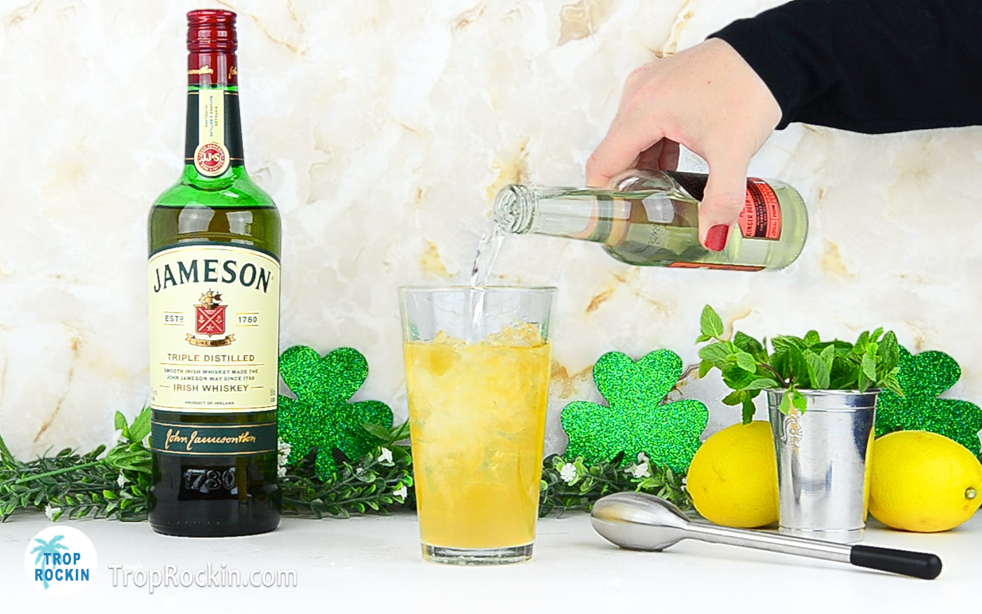 Pouring ginger beer into cocktail glass with lemonade and irish whiskey.