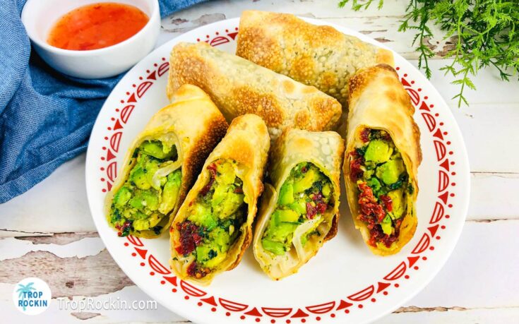 Air fryer avocado egg rolls on a serving plate with dipping sauce on the side.