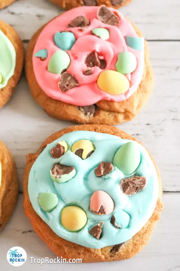 Upclose of two easter chocolate chip cookies. One with pink frosting and the other with pastel blue frosting.