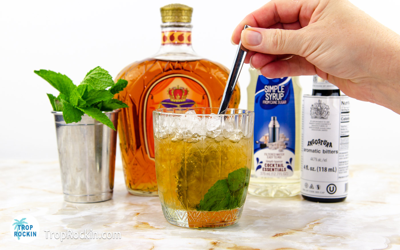 Stiring peach mint julep drink with a spoon.