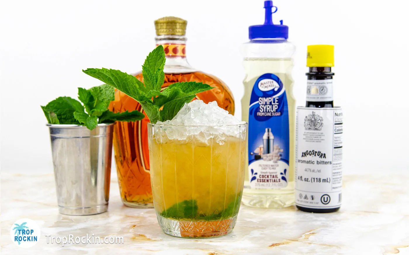 Peach mint julep drink with a mound of crushed ice on top and a mint sprig.