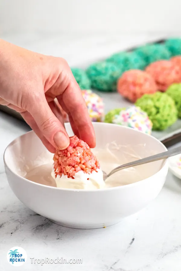 Dipping the large end of the rice krispie easter egg into the bowl melted white candy melts.