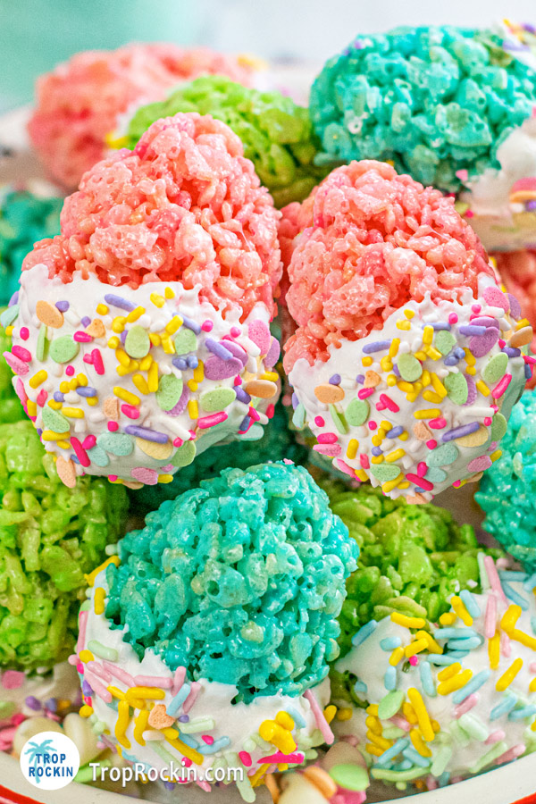 Up close look at easter egg rice krispie treats in various colors with bottom half dipped in white candy melts with added easter sprinkles.