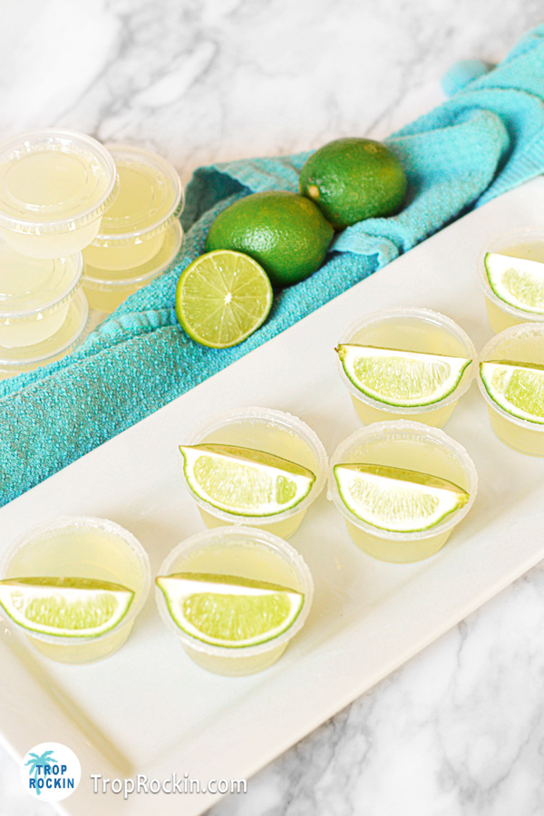 Margarita jello shots on serving tray with limes in the background.