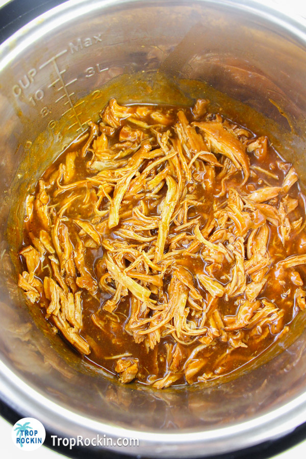 Shredded chicken inside the instant pot with sauce.