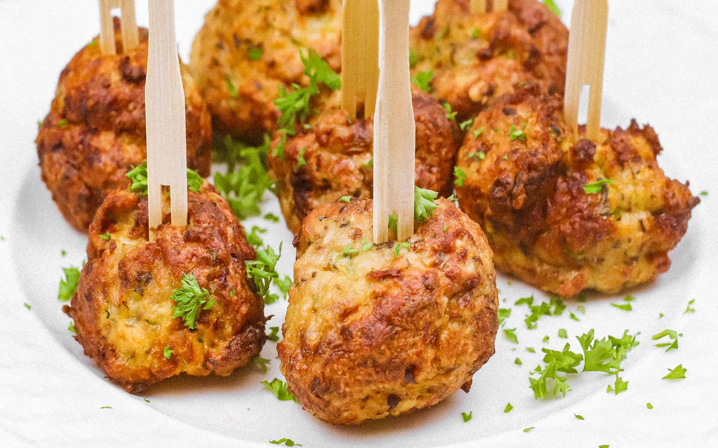 Air fryer chicken meatballs displayed on a white serving platter with wooden picks stuck in the top.