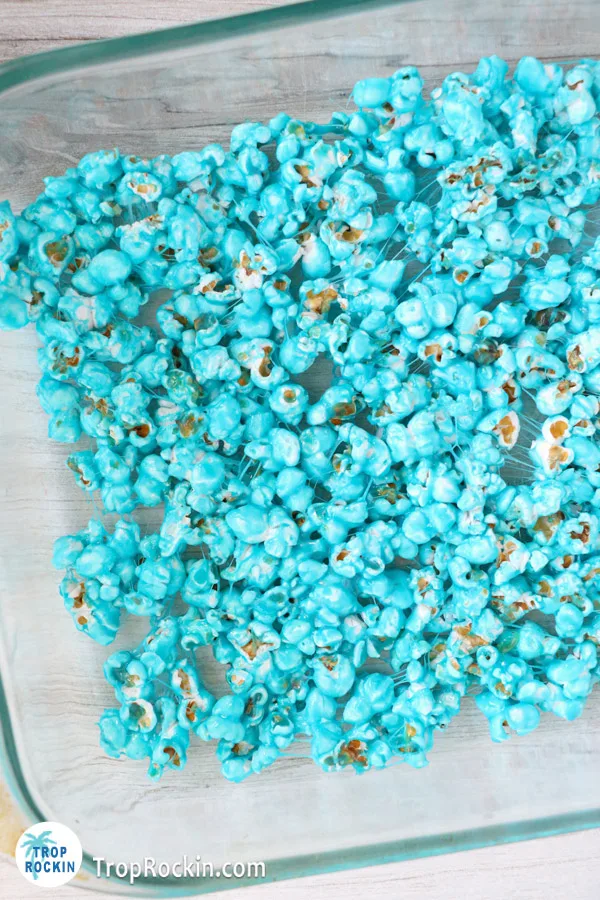 Blue popcorn pressed down into a single layer on the bottom of the greased baking pan.