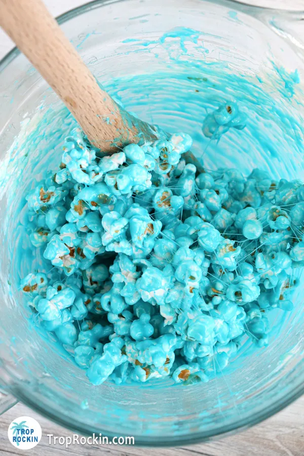 Popcorn added into the blue marshmallow mixture in the bowl.