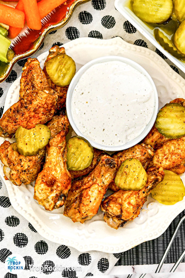 Closer photo of Nashville Hot Wings with pickles and a bowl of ranch dressing on a plate.