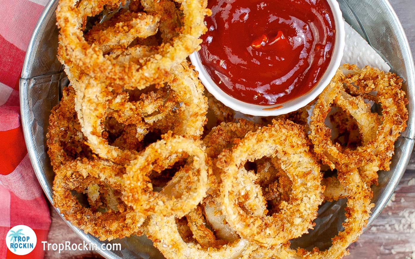 Tray full of air fryer onion rings and a small bowl of ketchup.