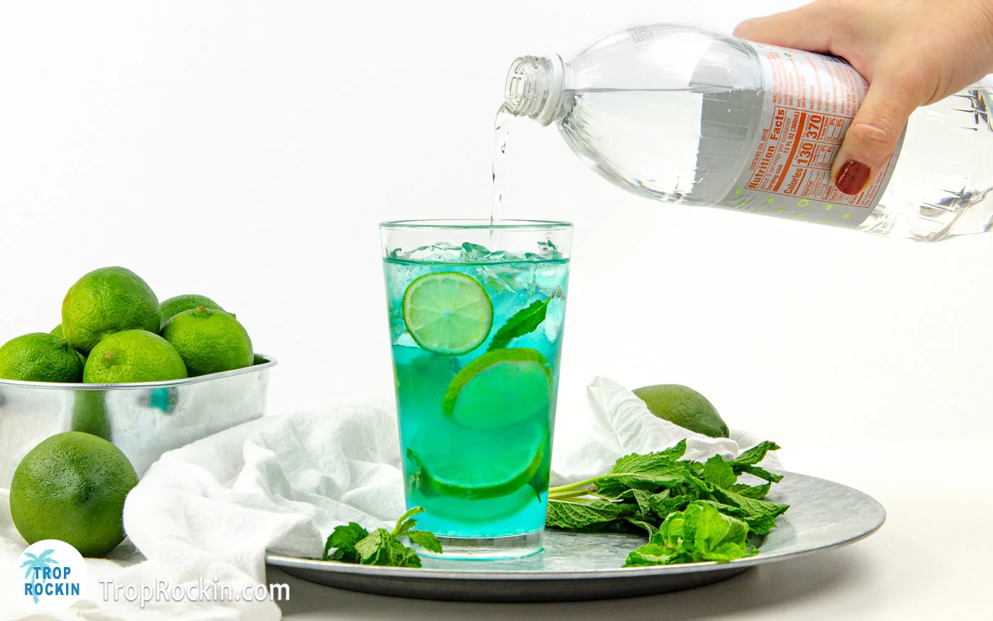 Pouring lime tonic into the drink glass.