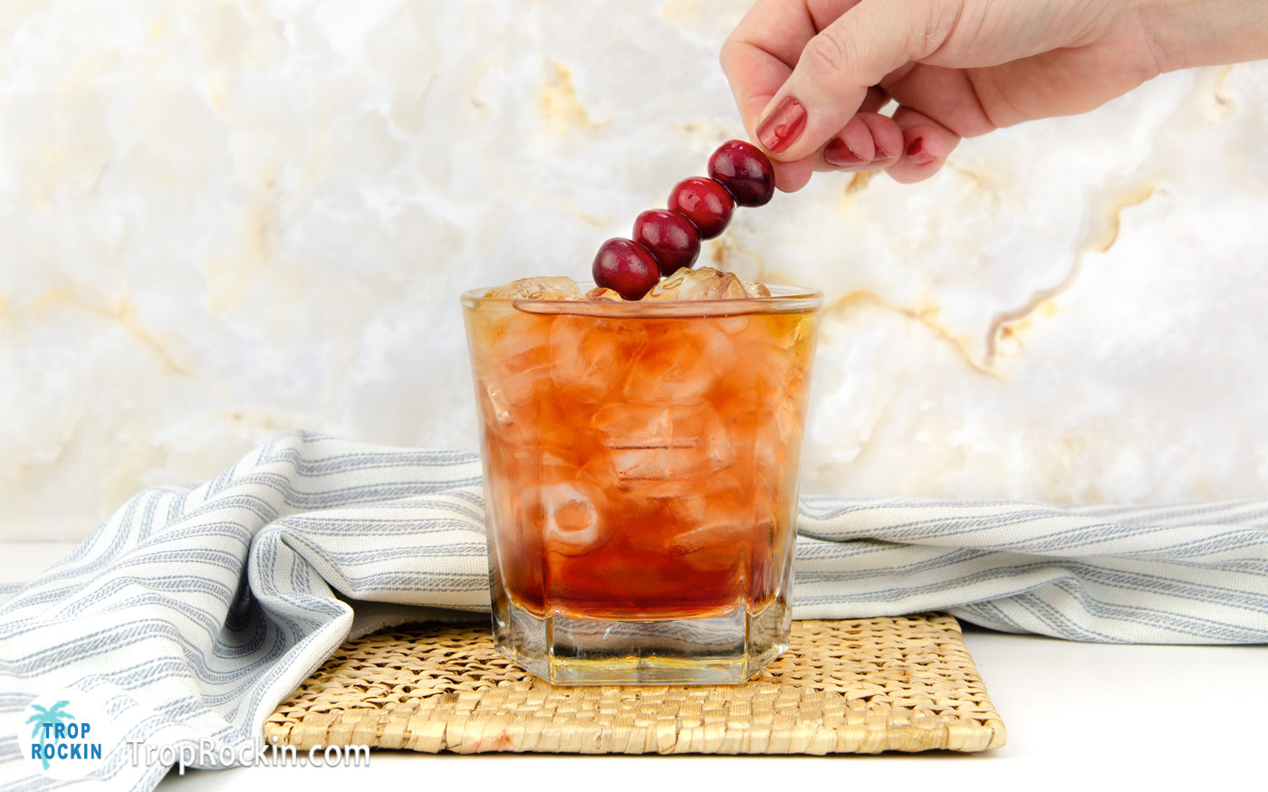 Placing a skewer of fresh cranberries on top of Crown and Cranberry drink.