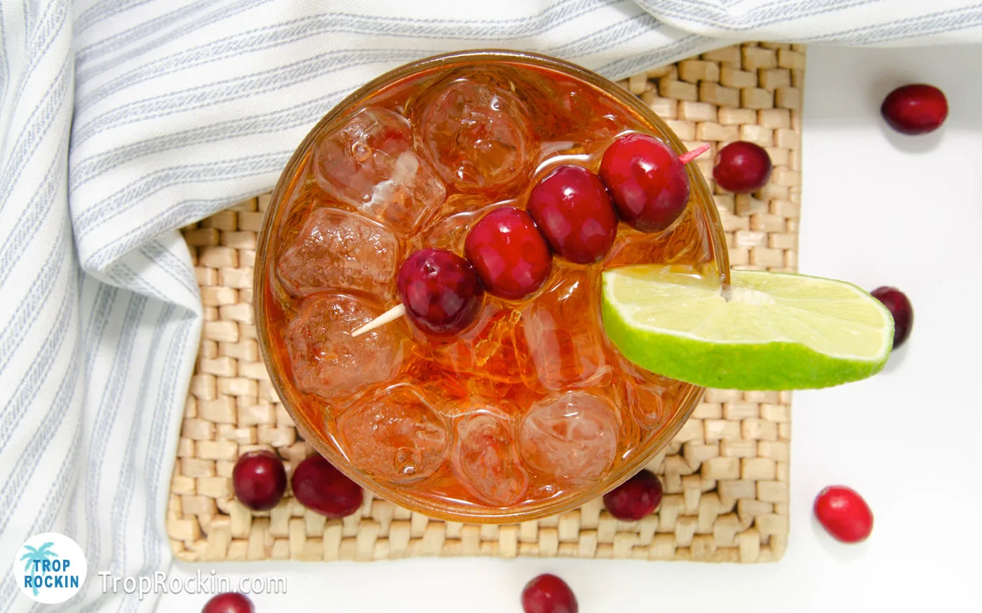 Top view of a Crown and Cranberry drink with skewer of cranberries and a lime wheel on side of the glass for garnish.