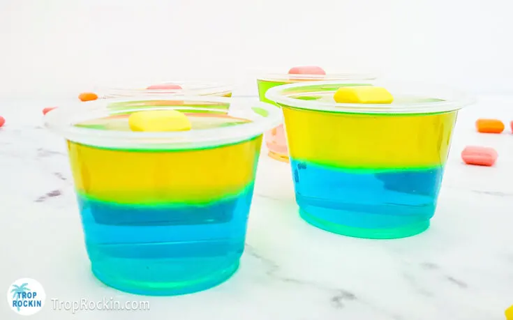 Two Starburst Jello Shots with blue raspberry jello on bottom and lemon jello on top for a layered jello shot topped with a yello starburst candy.
