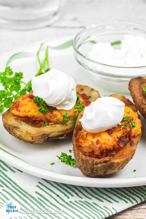 Two air fried potato skins on a plate topped with sour cream.