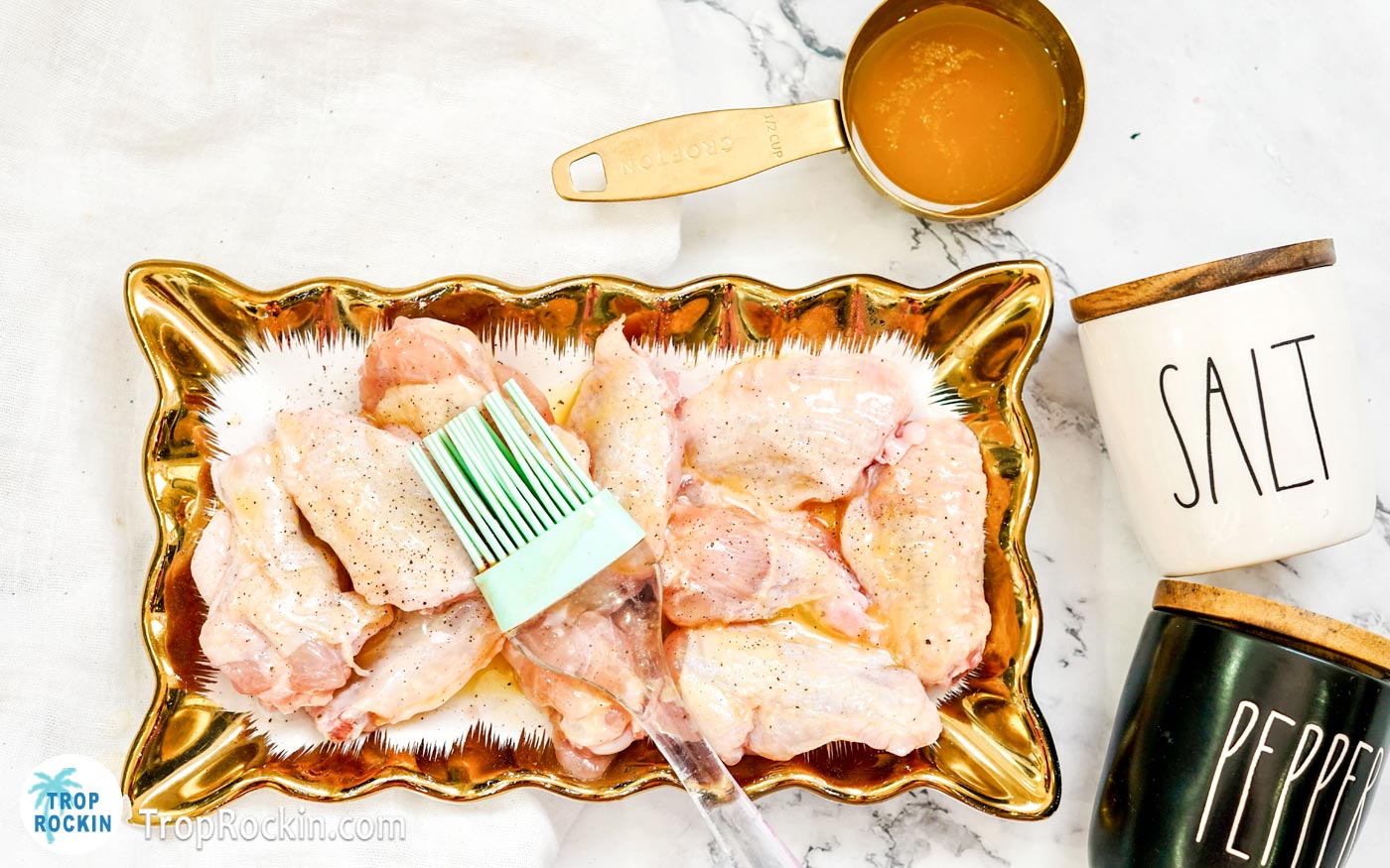 Raw chicken wings with butter brushed on with a pasty brush.