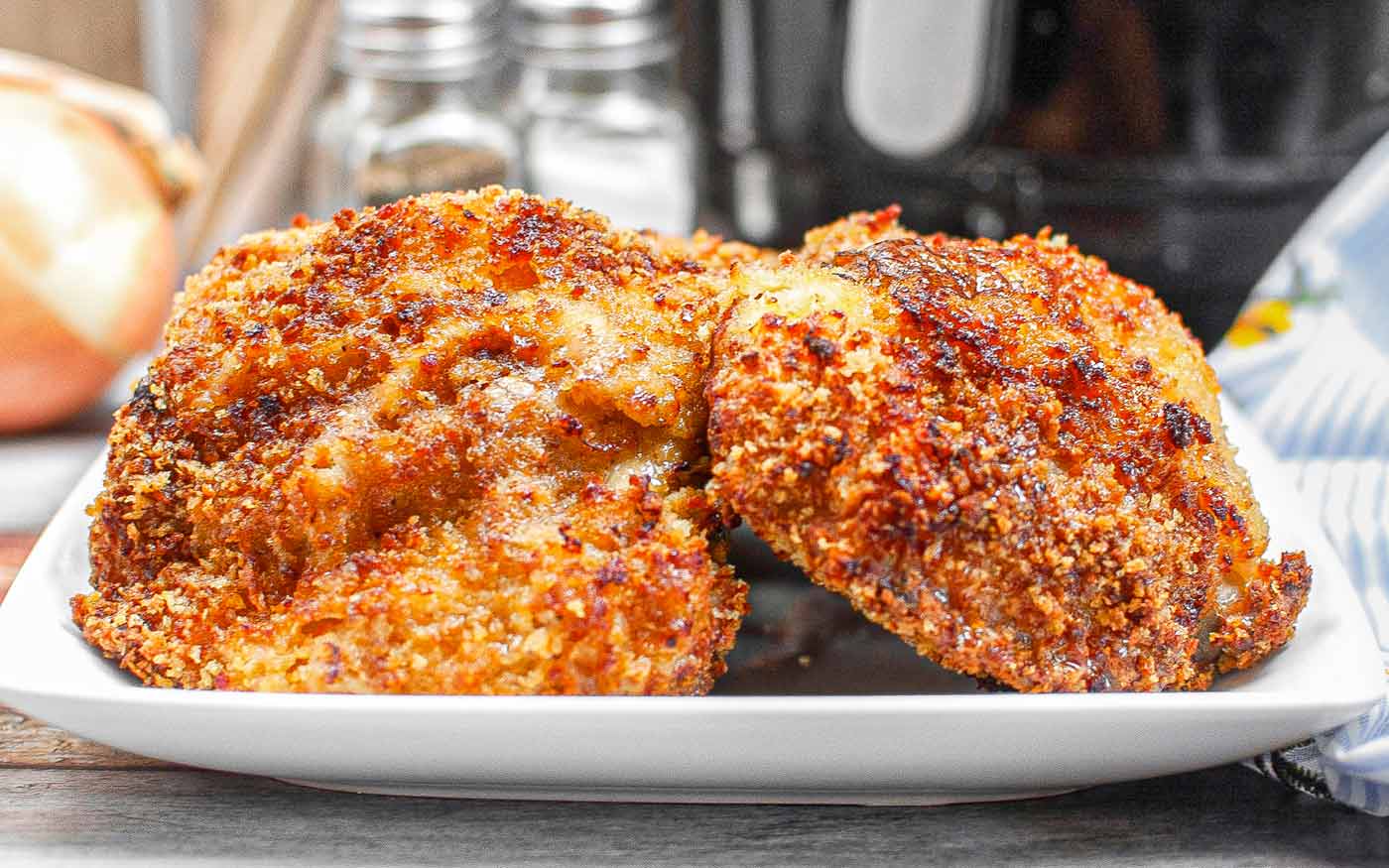 Air Fryer Panko Chicken Thighs on a white plate with the air fryer in the background.