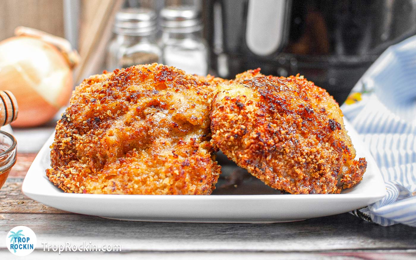 Air Fryer Panko Chicken Thighs on a white plate with the air fryer in the background.
