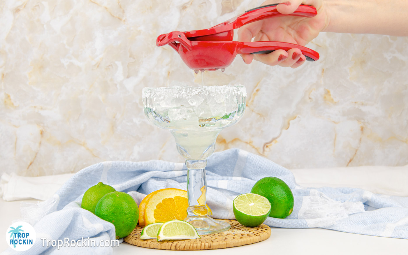 Using a lime squeezer to juice fresh limes into margarita glass.