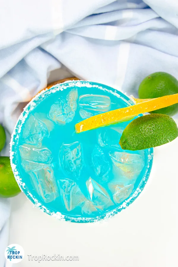 Top view of a blue curacao margarita with lime wedge and orange slice.