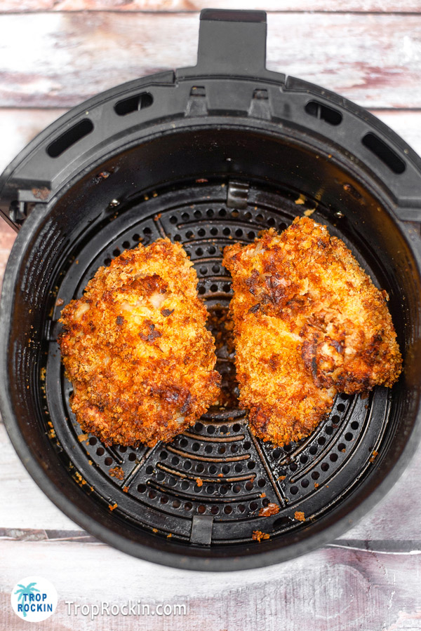 Two boneless chicken thighs air fried and sitting in the air fryer basket.