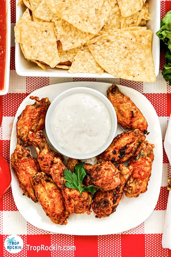 Bowl of tortilla chips and plate of air fryer mexican wings with ranch dressing in a small bowl.