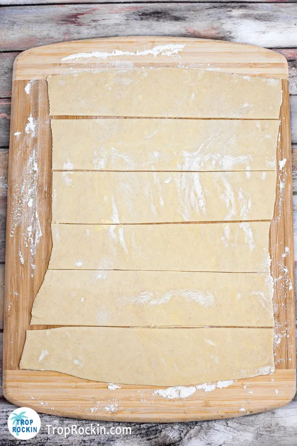Puff pastry rolled flat and cut into six strips on top of cutting board.