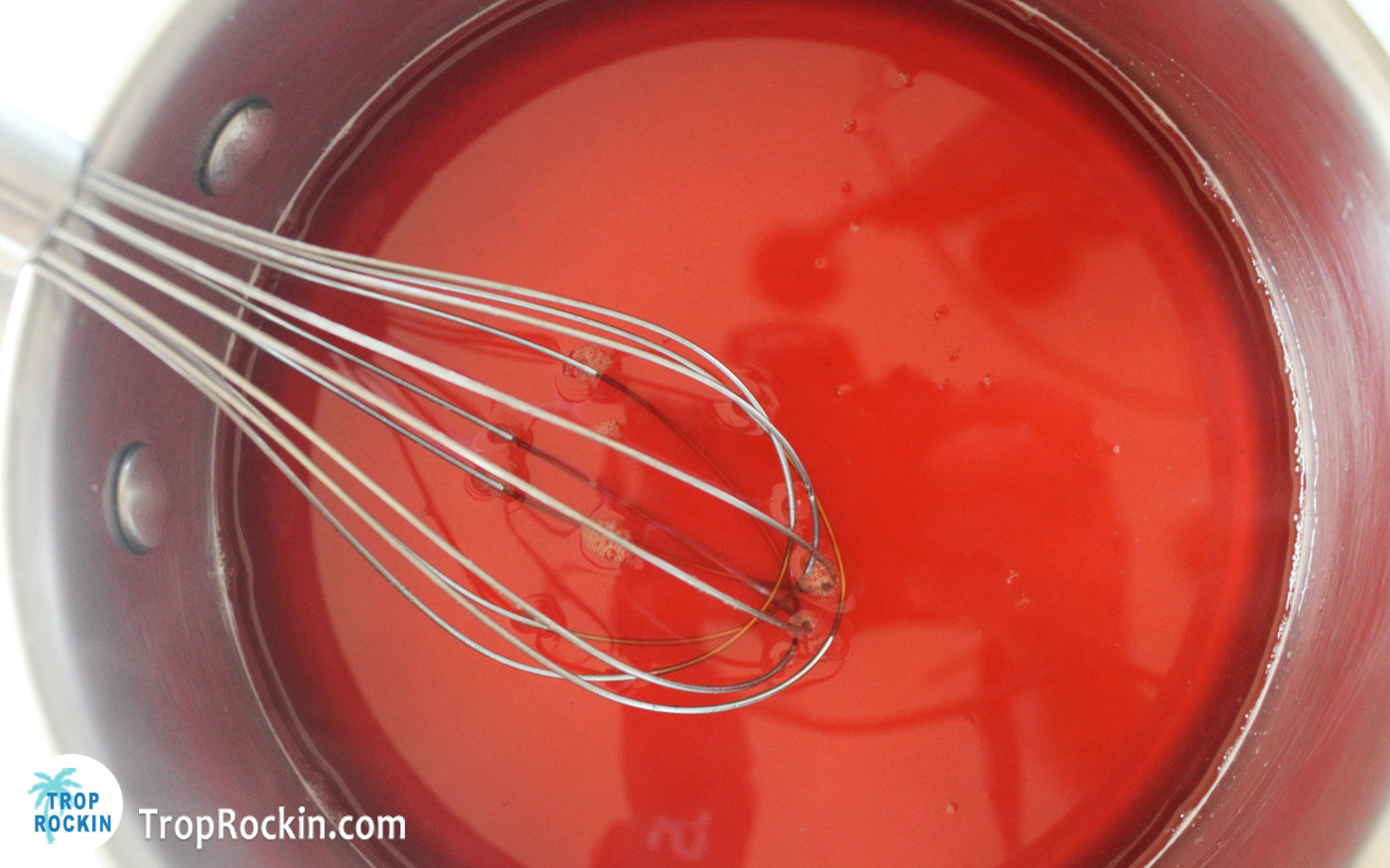 Orange jello in a sauce pan and using a whisk to stilr until dissolved.