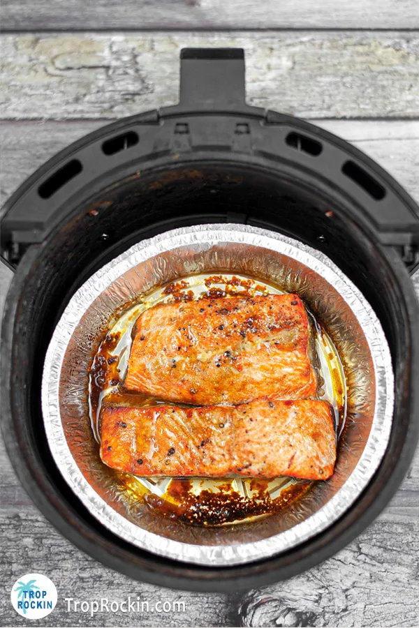 Two salmon fillets cooked inside the air fryer basket.