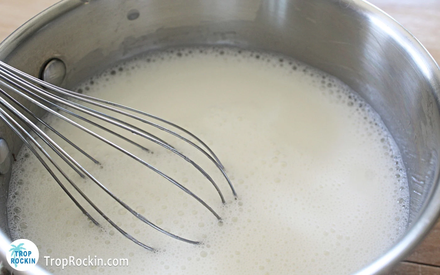 White jello mixture in saucpan with a whisk.