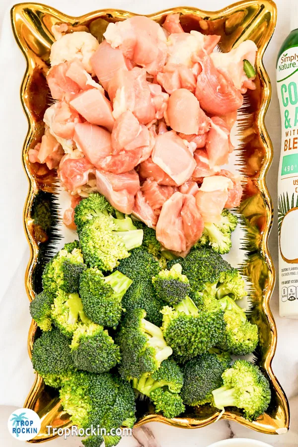 Raw cubed chicken and cut broccoli on a serving platter.