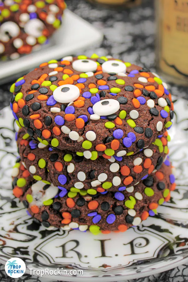 Three Halloween Sprinkle Cookies with eyeballs stacked on a black and white plate.