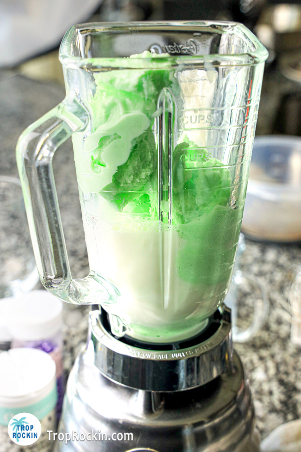 Lime sherbet and milk inside a blender.