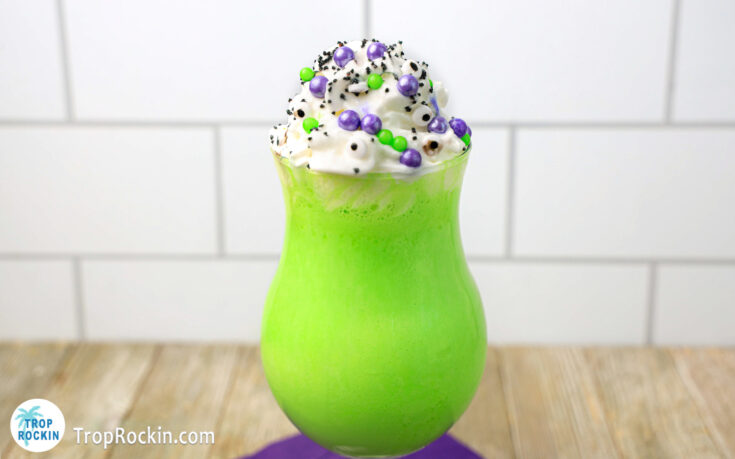 Hocus Pocus Halloween Milkshake is bright green in a tulip glass with whipped cream on top with sprinkles.