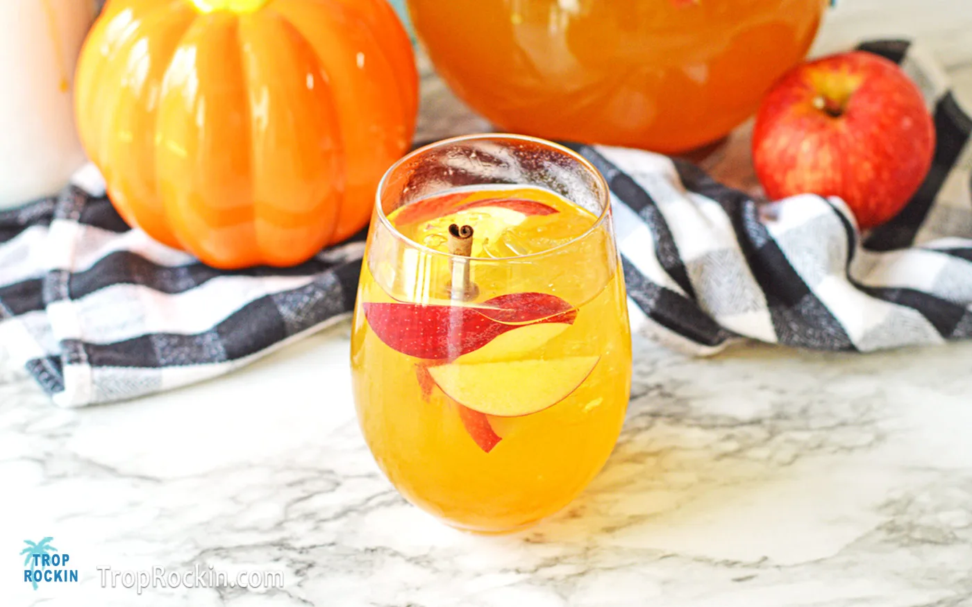 Pumpkin Sangria in a glass on counter top with decorative pumpkins in the background.