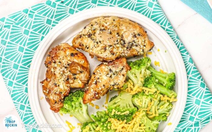 Air fryer boneless chicken thighs on a white plate with broccoli.