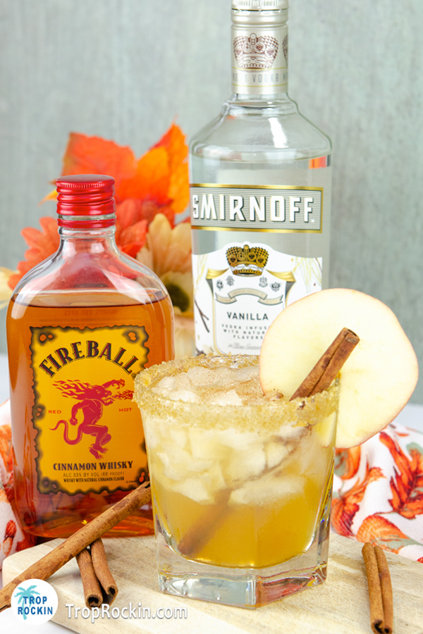 Apple pie drink with a bottle of Fireball Whisky and Vanilla Vodka bottles in the background.